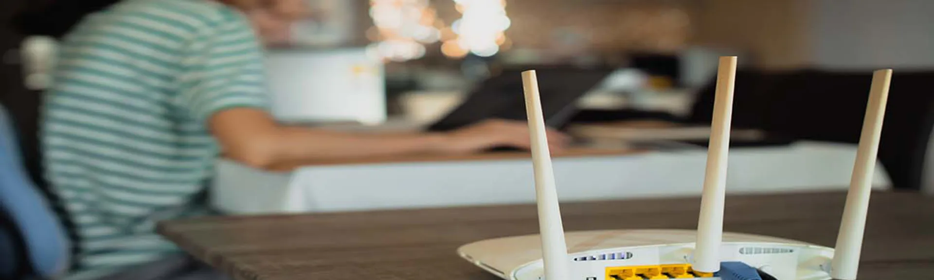 Person using laptop with broadband router on table 